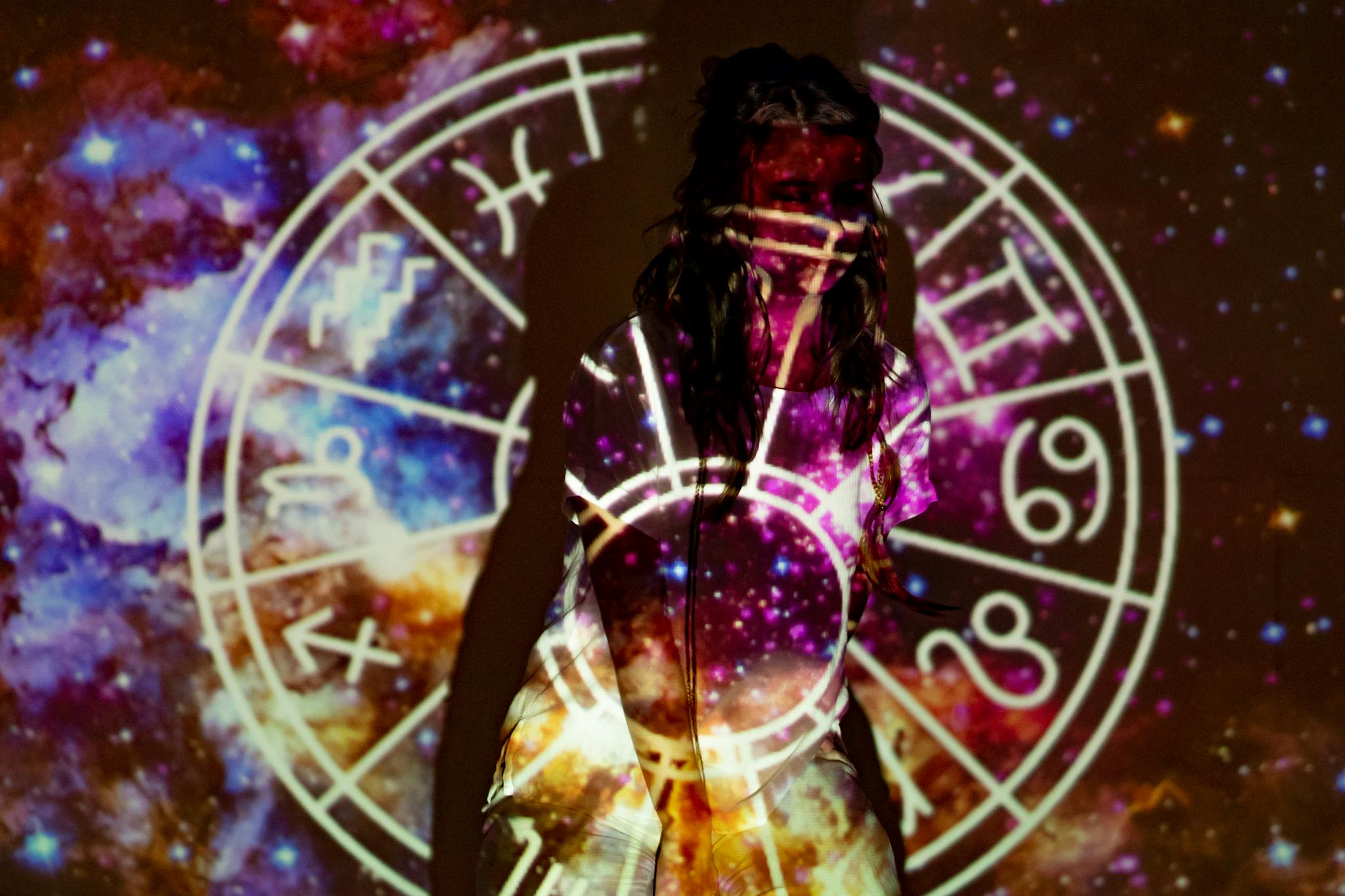 A mystical image of a woman enveloped in celestial projections and astrological symbols.